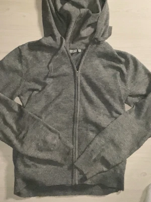 Grå hoodie med dragkedja från RYVLS - Mysig grå hoodie från RYVLS Stockholm i storlek 158/164. Tröjan har dragkedja framtill, huva och ribbade muddar vid ärmslut och nederkant. Perfekt för chill dagar och enkel att matcha med jeans eller mjukisbyxor.