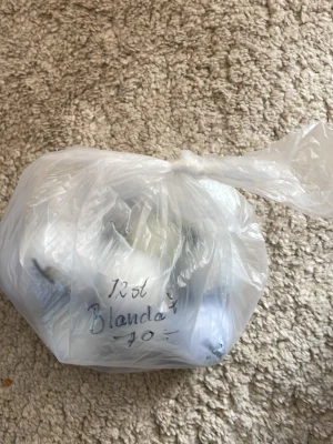 Påse med blandade bestick - En genomskinlig plastpåse fylld med 12 stycken blandade bestick. Perfekt för dig som behöver extra gafflar, knivar eller skedar till köket eller picknicken. Påsen är knuten upptill och innehållet syns delvis genom plasten.