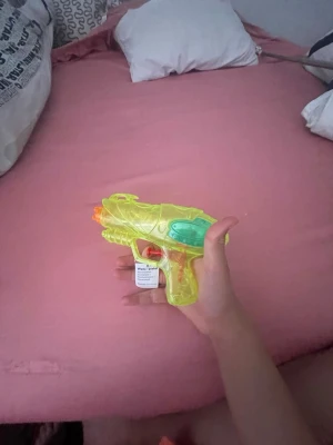 Neongrön vattenpistol i plast - Säljer en neongrön vattenpistol i genomskinlig plast med orange och turkosa detaljer. Perfekt för vattenlekar utomhus. Pistolen är lätt att fylla på och har ett smidigt grepp som passar de flesta händer.