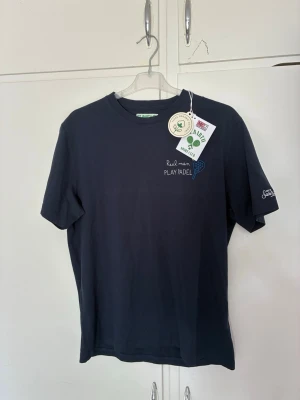 Mörkblå t-shirt St. Barth Sport Club - Mörkblå t-shirt från St. Barth Sport Club med broderad text 'Real men PLAY PADEL' och ett litet padelracket på bröstet. Klassisk passform och rund hals. Perfekt för dig som gillar sportig stil.