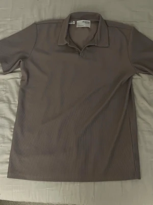 Ribbad brun skjorta från Selected Homme - Säljer en ribbad brun skjorta från Selected Homme i storlek M. Skjortan har korta ärmar, klassisk krage och är tillverkad i ett mjukt material som känns skönt mot huden. Perfekt för dig som gillar stilrena och enkla plagg.