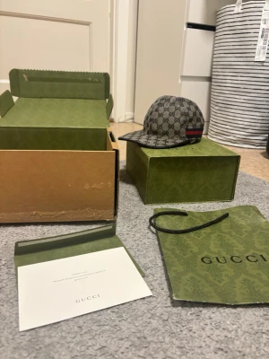 Gucci GG Navy Canvas - Säljer en snygg Gucci keps i GG Supreme-mönster med klassisk beige och brun färg samt en röd och grön rand på sidan. Kepsen har böjd skärm och justerbar rem bak. Materialet är canvas med läderdetaljer. Perfekt för dig som gillar exklusiv streetwear. Behöver en tvätt och knappen där uppe saknas annars felfri keps, har tyvärr ingen tvättpåse för kepsar men de är lätt att fixa och kostar bara nån hundring. Kom med bud om du är seriös!😁✌️