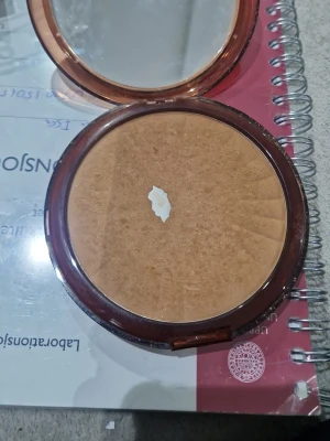 IsaDora Bronzing Powder bronzer - IsaDora Bronzing Powder i en rund, brun plastförpackning med spegel i locket. Pudret har en varm, gyllenbrun ton som ger huden en solkysst look. Perfekt för att framhäva ansiktets konturer och skapa glow. Den är använd 
