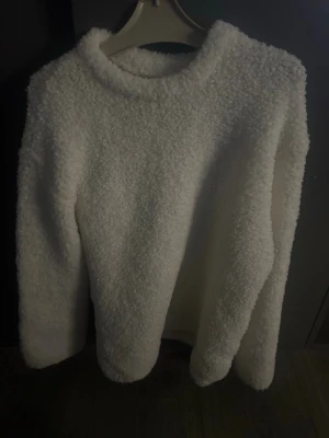 Fluffig stickad tröja - Supermjuk och fluffig vit stickad tröja från Kappahl. Tröjan har rund halsringning och långa ärmar, perfekt för dig som gillar mysiga och stilrena plagg. 