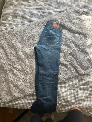 Blå slim straight jeans Jack & Jones - Säljer ett par blå slim straight jeans från Jack & Jones. Klassisk femficksmodell med snygga kontrastsömmar och läderpatch bak i midjan. Jeansen har normalhög midja och raka ben, perfekta till vardagslooken. Ett litet hål i rumpan