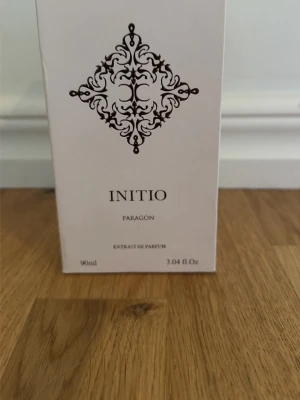 Initio Paragon Extrait de Parfum 90ml - Initio Paragon Extrait de Parfum i en elegant vit flaska med fyrkantig form och dekorativt mönster på framsidan. Flaskan har en stilren design och kommer i en matchande vit förpackning. Perfekt för dig som gillar exklusiva dofter. Endast test sprutad så cirka 85 ml kvar 