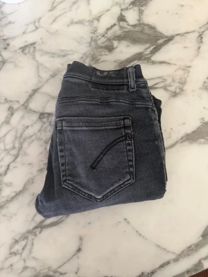 Mörkgrå slim fit jeans - Säljer ett par mörkgrå slim fit jeans med klassisk femficksdesign och snygga slitningar. Jeansen har en modern tvätt och raka ben, perfekta för en avslappnad men ändå stilren look. Materialet är mjukt och stretchigt för extra komfort.
