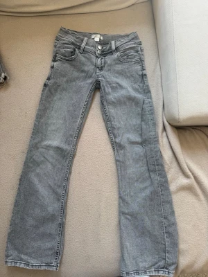 Grå jeans från Gina Tricot - Säljer ett par grå jeans från Gina Tricot i storlek 146. Jeansen är flair och low waist , klassisk femficksmodell och silverfärgade knappar. Materialet är denim med en mjuk känsla och snygg tvättad look.