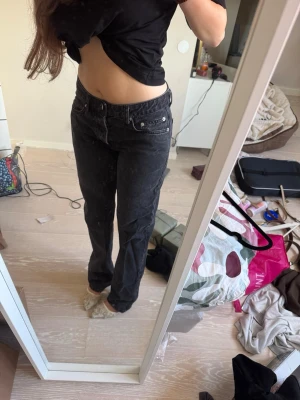 Svarta raka jeans med hög midja - Säljer ett par svarta jeans med rak passform och hög midja. Jeansen har klassisk femficksdesign och silverfärgade nitar. Perfekta för en avslappnad och trendig look. Materialet är denim i bomull.