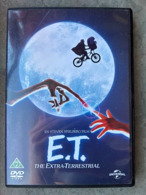 E.T The extra material DVD - E.T. The Extra-material på DVD. Filmen är regisserad av Steven Spielberg. Ljudspår på engelska och danska. Undertexter på engelska och danska. Bonusmaterial inkluderar introduktion av Steven Spielberg och liveupptagning av John Williams musik till filmen.  Finns på språk: Engelska, Danska   OBS!! skivorna är begagnade så det kan förekomma repor/hairlines på skivorna, men då jag kollar igenom alla filmer jag säljer garanterar jag att alla funkar felfritt om inget annat står! :)