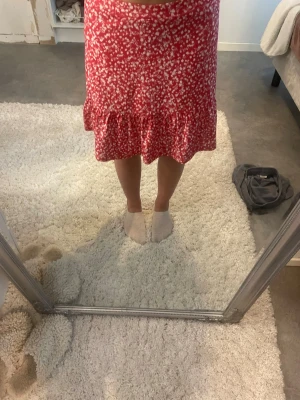 Blommig mid kjol - Blommig röd kjol som når till knäna, storlek XS