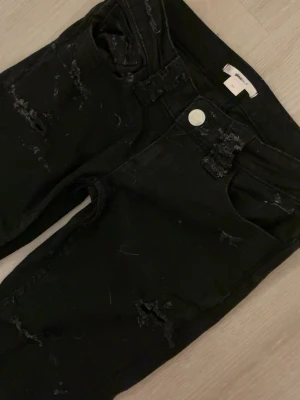 Svarta slitna bootcut jeans - Säljer ett par svarta bootcut jeans med slitningar och hål 🩷