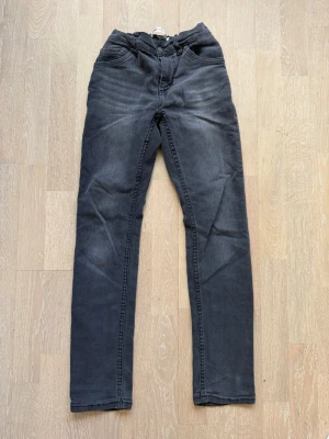 Mörkgrå raka jeans - Snygga mörkgrå jeans med rak passform och klassisk femficksdesign. Jeansen har diskreta slitningar och en enkel look som passar till det mesta. Tillverkade i ett mjukt denimtyg med lite stretch för extra komfort.