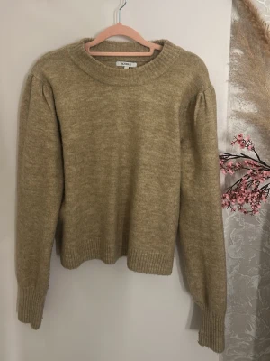 Beige stickad tröja med puffärm - Mysig beige stickad tröja med rund halsringning och diskreta puffärmar.