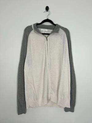 Calvin Klein Bomull & Kashmir Zip Cardigan Off White/Grå XL - Calvin Klein Bomull & Kashmir Zip Cardigan Off White/Grå XL  • Storlek: XL • Färg: Off white med grå ärmar och grå krage • Passform: Regular Fit • Krage: Hög ribbad krage • Material: 85 % bomull, 15 % kashmir  Skick: Plagget är i ett fint skick med några fläckar som syns på bild. Eventuella anmärkningar anges alltid tydligt i beskrivningen och visas på bilderna.  Nypris: Cirka 2 000 kr.  📦 Skickas snabbt och packas omsorgsfullt. 💬 Hör gärna av dig om du har frågor eller vill se fler bilder. 🤝 Sa