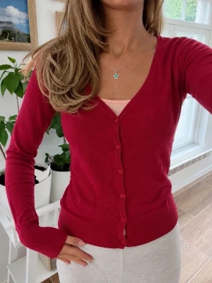 Zara röd stickad kofta – Stl M - Finstickad röd kofta från Zara i storlek M. Klassisk modell med knappar framtill som passar lika bra öppen som stängd. Perfekt att bära över ett linne, klänning eller till jeans. Mjuk, bekväm och i fint skick.