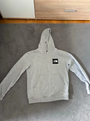 Grå hoodie från The North Face - Snygg grå hoodie från The North Face med klassisk logga på bröstet. Vid funderingar eller frågor är det bara att höra av sig!