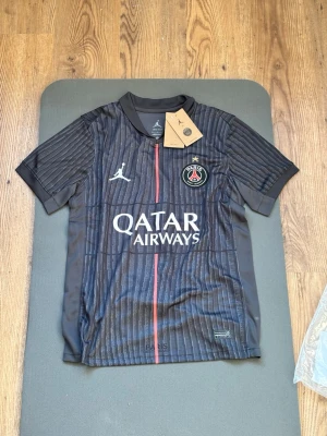 PSG - 4th choice - Säljer en Paris Saint-Germain 4th choice - 2025/26 tröja. En Dri-fit premium material tröja med svart färg detaljerat med rött. Fraktas iväg i en extra skyddat fraktpåse. Kom gärna med bud.