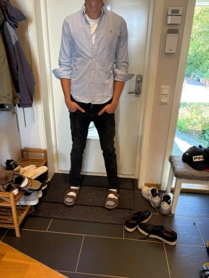 Ljusblå skjorta med knappar Ralph lauren - Säljer en stilren ljusblå skjorta från Ralph lauren med klassisk krage och knappar framtill. Skjortan har lång ärm. Perfekt för dig som gillar en clean och enkel look.