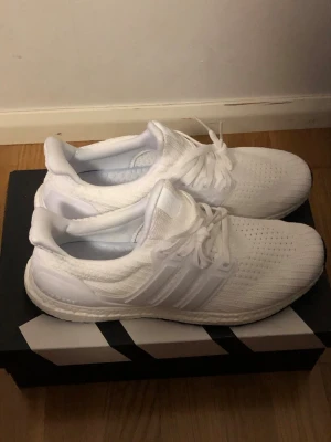 Helvita sneakers med stickad ovandel - Snygga helvita sneakers med stickad ovandel och klassisk siluett. Skorna har vita snören, diskreta ränder på sidorna och en bekväm, dämpad sula. Perfekta för dig som gillar en clean och sportig look.