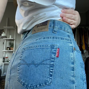 JEANSKJOL MED BRODERI - Jeanskjol i midilängd med supersöta broderier på sidorna! Nyskick även fast det är secondhand och säljs pga att den är lite för stor för mig!🦋⚡️🌸🌼🫐