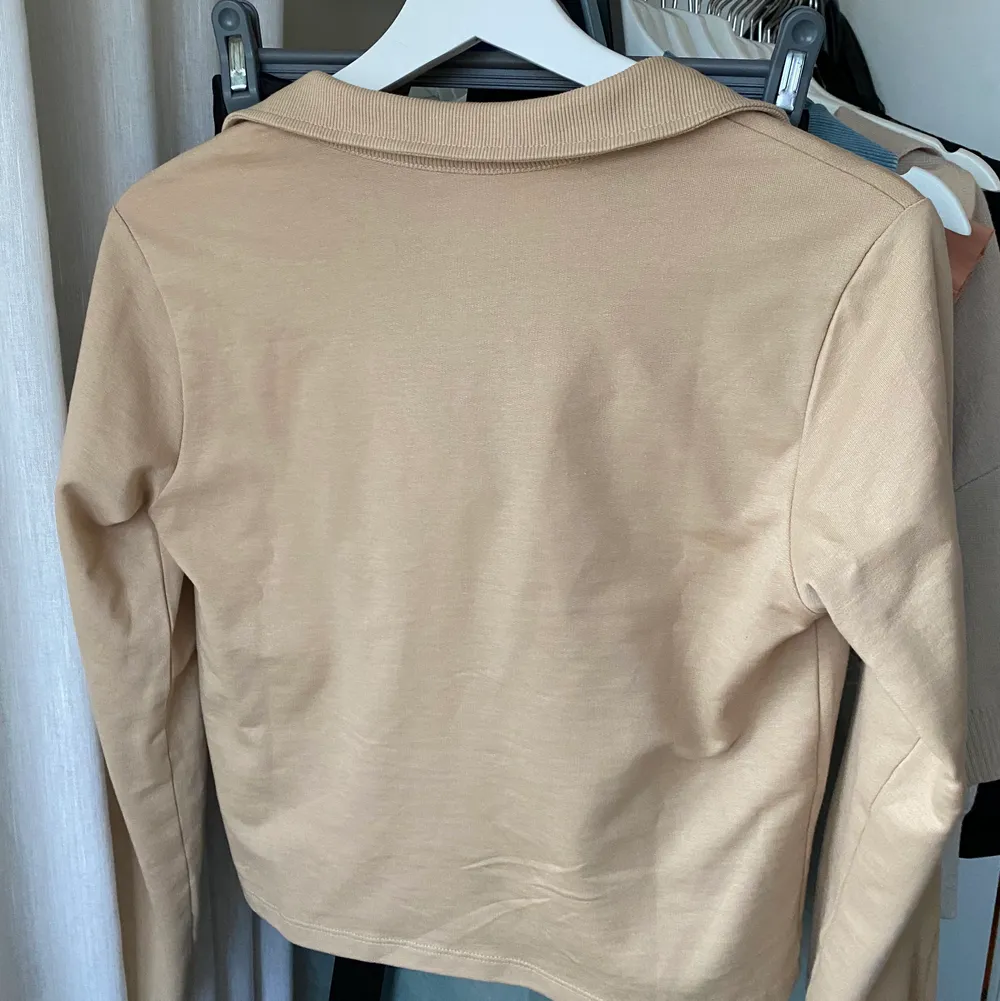 Beige topp med trendig tenniskrage. Använd en gång, i väldigt bra skick. Väldigt snygg modell som slutar precis där midjan på byxorna börjar. Köpt för 399 kr. Finns flera olika fraktalternativ ❤️. Toppar.