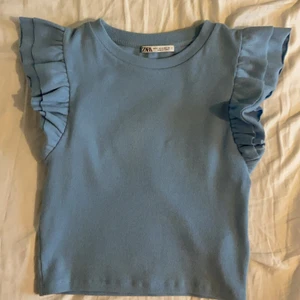 Topp ifrån Zara strl s - Säljer denna blå rivbade topp med volanger ifrån Zara, köpt i somras och endast använd 1 gång. Säljer för att den inte kommer till användning. Nypris 69kr