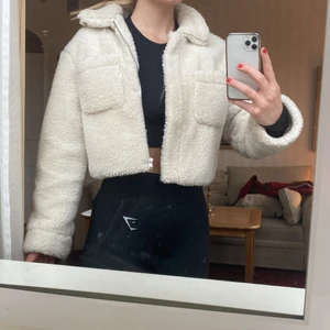 Croppad Teddy jacka - En mysig croppad teddyjacka i gott skick från NAKD. Säljer pga att jag inte använder så ofta. Två fickor framtill. Storlek 36.