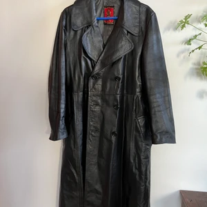 VINTAGE SKINN TRENCHCOAT  - Trenchcoat i äkta läder. (Producerad i Dalarna) köpt på secondhand- dock nyskick! Storlek 52, brukar ha M/ L och denna satt bra vid axlarna men lite lång vid armarna- men går bra att vila upp- se bild. 