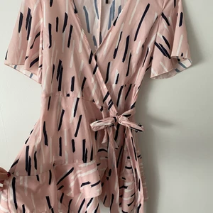 Rosa wrap around klänning - Oanvänd rosa söt wrap around klänning från asos bohoo i storlek 42 men lite liten i storlek  ! Lite kort i längd för min del! Volanger nertill och två snören för wrap around!