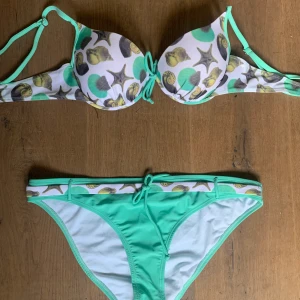 Bikini - En turkos bikini med snäckor på. Nyskick. Överdelen är 80B Underdelen står XL, men skulle säga att den borde passa M/L också. 40kr + frakt 