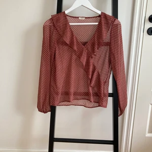 Blus från Systemaction inköpt i Palma - Strl: S V-ringning med volang och ballongärm mönstrad vinröd