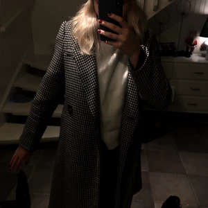 Dogtooth kappa - Svart och vit mönstrad kappa från stradivarius. Säljer då den inte kommer till användning. Det är ett hål i sömmen på en innerficka som går att sy igen enkelt, annars är kappan i nyskick. Köparen står för frakt💕💖