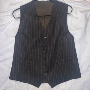 Brun randig kostymväst  - En jättesnygg brun randig kostymväst, köpt på secondhand. Har tyvärr inte kommit till användning och därmed säljer jag den (men är i väldigt bra skick). Justerbart knäppe bak. Säljer för 90kr. Köparen står för frakten😜💓