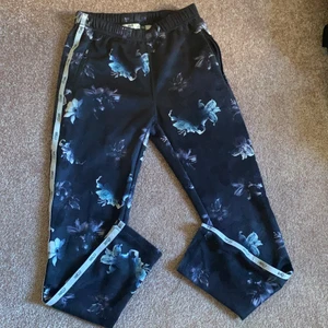 Snygga svarta träningsbyxor 💗 - Svarta träningsbyxor med blommor på. Storlek 134/140. Är i helt ok skick men säljs lite billigare eftersom tyget är lite raffsigt. Köpare står för frakt 💗🍀
