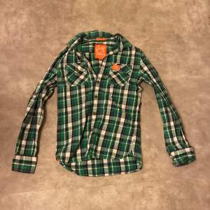 Superdry skjorta i grön rutig färg med orangea detaljer. Storlek small. Använd men i bra skick! Kan skickas men köparen står för frakten.