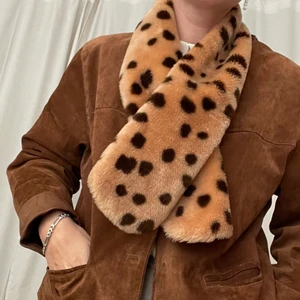 Fuskpälskrage/scarf/halsduk - Krage eller halsduk i varmt beige fuskpäls med mörkbruna prickar. Köpt vintage och har lite patina men är i gott skick. Aldrig använd av mig. Kan bäras öppen, stängd, utanpå valfri jacka, istoppad. Bra att ha