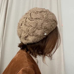 Stickad beige basker/mössa  - En stickad basker köpt i designbutik i Köpenhamn. Använd men i gott skick. Är one size men har en icke åtsittande, skön passform. Gjord i Tyskland av märket Seeberger. Värmer  