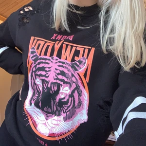 Collegetröja från Ginatricot - Jättesnygg collegetröja med tryck av ett tigerhuvud. Storlek XS men passar även S. Kommer tyvärr inte till användning längre. Modellen har slitningar på 3 olika ställen, syns nog bäst på andra bilden.