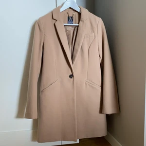 En beige kappa - En beige stilren kappa perfekt till hösten. Andvänd ett fåtal gånger.