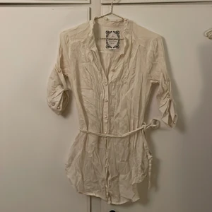 Snygg blus med 3/4 ärm strl.M - Snygg blus/skjorta i tunnare tyg. ”Skärpet” kan tas bort. 3/4 ärm. Plagget är ostruket på bilden fast i mycket gott skick.  