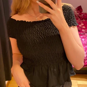 Fin sommarblus med volang  - Svart sommarblus med volang för nedan. Tyget är väldigt stretchigt. Fint skick