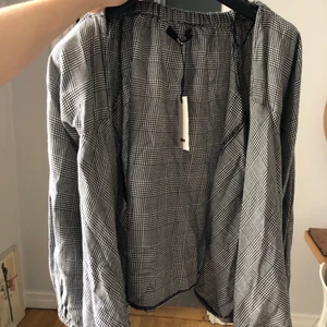Snygg omlott rutig blus  - Rutig blus som knyts 2 varv. V-ringad med stora ärmar.