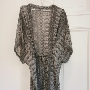 Kimono grå ormskinnsmönstrad - Tunn och luftig kimono med grått ormskinnsmönster. Knytband i midjan som både går att dra åt och ta bort helt. One size, rymlig. Köparen står för frakten, kan även hämtas i Malmö! 
