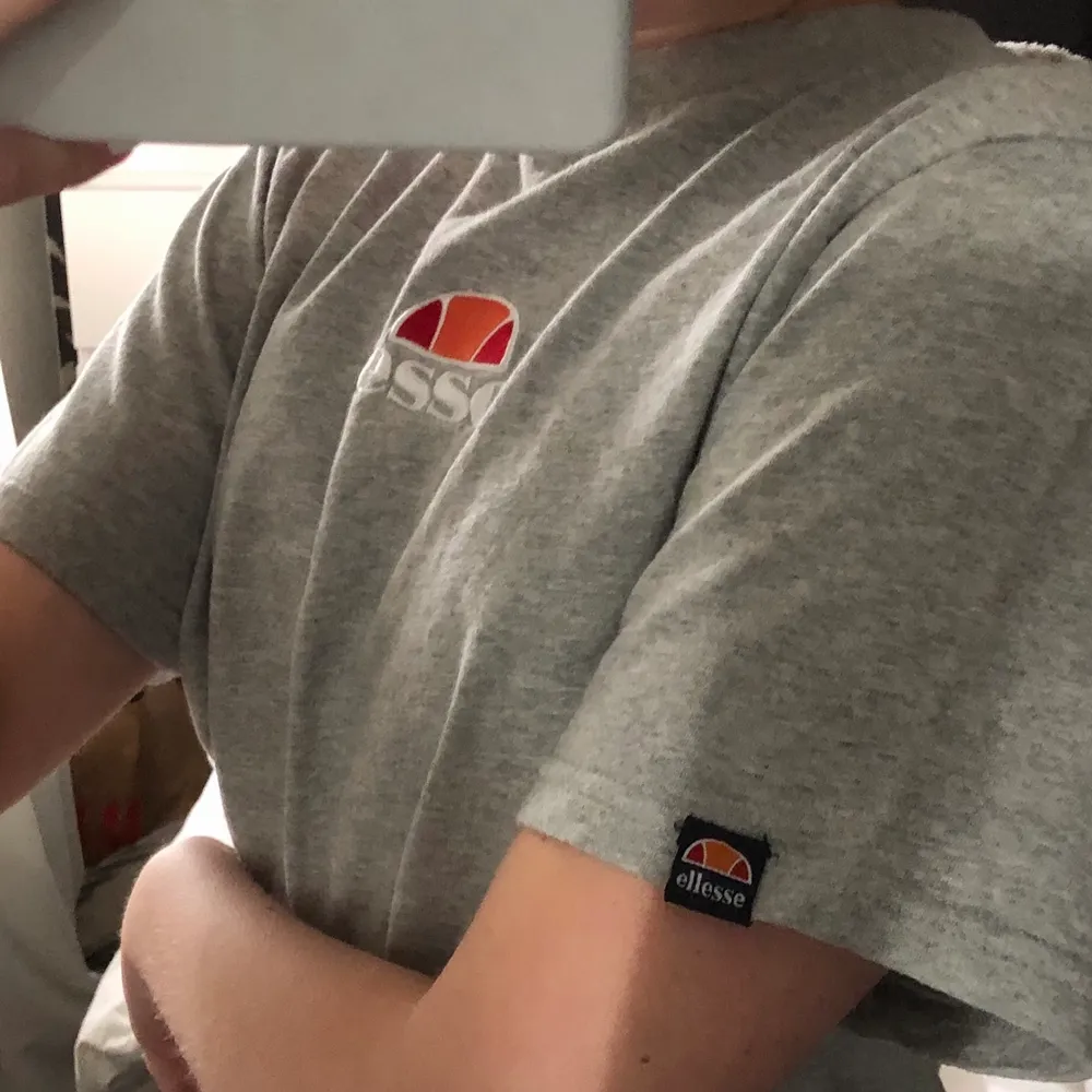 En crooped t-shirt som är grå med text ”ellesse” där fram och ett liten mindre text på ena sidan av ärmen. Skön tröja men säljer då den aldrig kommer till användning. Frakt förekommer . T-shirts.