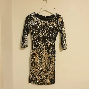 Paljettklänning - En snygg klänning med silvriga och svarta paljetter och öppen rygg, sparsamt använd.