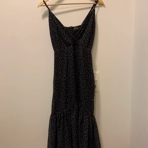 Vitprickig svart långklänning - Säljer denna långklänning som är köpt på Asos! Använd endast 1-2 gånger. Superfin men inte helt min stil. Jag har klippt av ett tyglager längst ner på klänningen så den passar lite kortare personer, ca 155-165 cm.