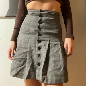 Grå kjol med veck och knappar - Grå kjol med veck och knappar från United colors of benetton. Sitter väldigt bra på mig som är storlek M/S, skulle dock säga att det är en S. Sitter tajt runt midjan men enligt mig på ett bra sätt:) tycker den sitter lite som en korsett fast bekvämare. Fraktar eller möts upp i Sthlm❣️