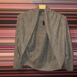 Grå glittrig kofta  - Grå glittrig kofta storlek L men mer som en XS-S, kort i ärmarna. Köpt på Vero Moda! Aldrig använd så bra skick! Säljer för 90kr eller buda! Köparen står för frakten! Frågor skriv till mig! 