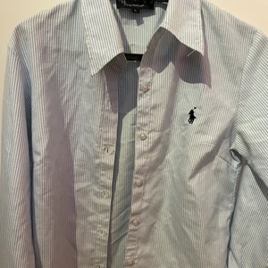 Polo skjorta  - En fin ljus blå randig skjorta. Storleken på skjortan är L men funkar som S